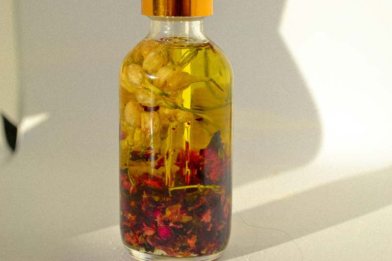 Close-up of glass jars filled with organic moisturizers beside fresh aloe vera leaves and chamomile flowers on a wooden surface